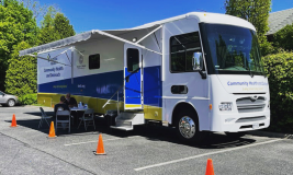 Mobile health bus parked in Library parking lot with blue skies